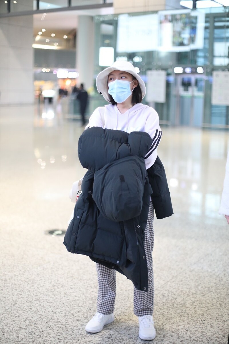 文淇一袭白色连帽卫衣现身机场，头戴帽子遮不住甜甜的笑容